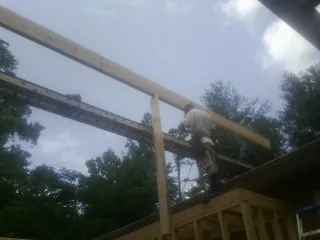 Carpenter setting a ridge beam over a new addition frame — Ice Dam Removal by Roofing Brothers in Otho