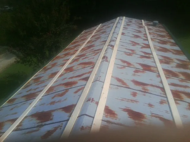 Rusted metal roof panels with new wood purlins before replacement — Storm Damage Roof Repair in Otho by Roofing Brothers