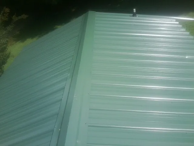 New green metal panels meeting at the ridge of a roof — Flat Roof Repair work by our crew in Otho