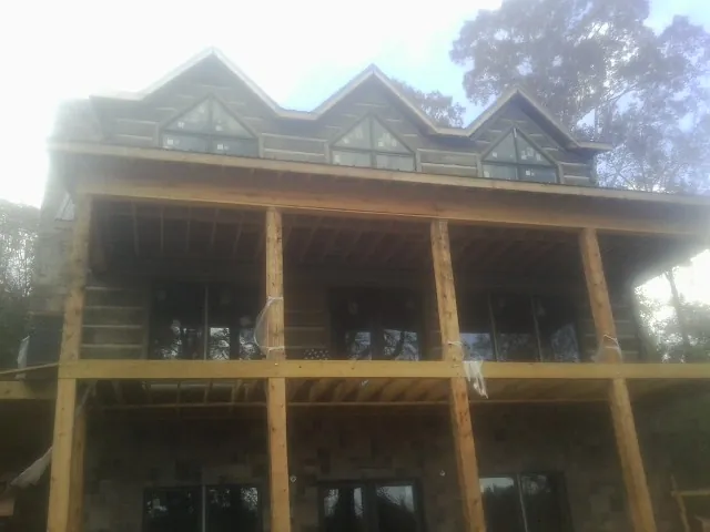 Dormers and porch framing on a large log home under construction — Roof Coating work by our crew in Otho
