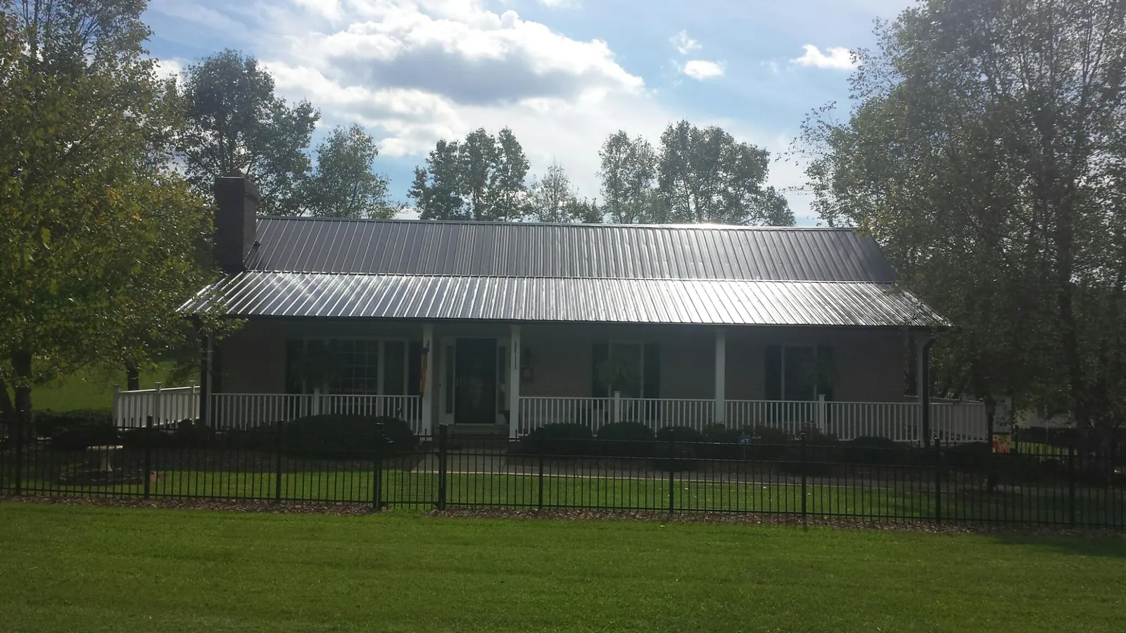 Gray metal roof on a brick ranch with a full width front porch — Gutter Guard Installation work by our crew in Otho